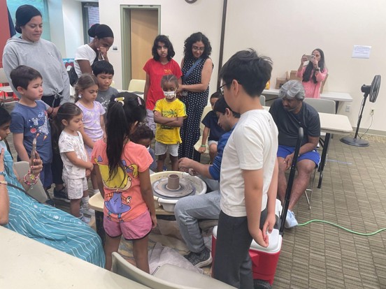 A library meeting room full of children watching a pottery demonstration